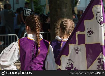 Violet Flag near Little Girls in Uniform with Braid Hairstyle during Parade.. Violet Flag near Little Girls in Uniform with Braid Hairstyle during Parade