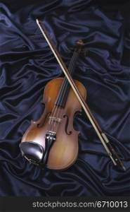 Violin and a bow on blue fabric