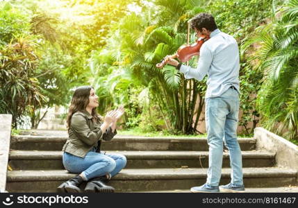 Violinist man playing a melody to a girl sitting on the stairs. Man playing violin for girl sitting on stairs outside. Concept of man playing violin to people on the street