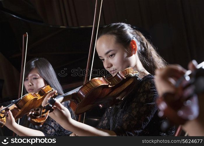 Violinists playing during a performance, head and shoulders