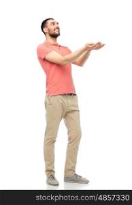 virtual, augmented reality and people concept - happy man in polo t-shirt holding something imaginary on hands over white background