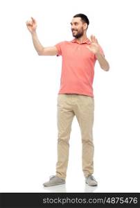 virtual, augmented reality and people concept - happy man in polo t-shirt touching something imaginary over white background