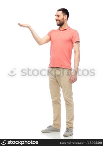 virtual, augmented reality and people concept - happy man in polo t-shirt holding something imaginary on hand over white background