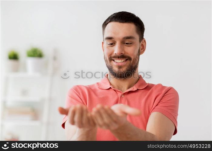 virtual reality, entertainment and people concept - happy man holding something imaginary on palms at home. happy man holding something imaginary at home