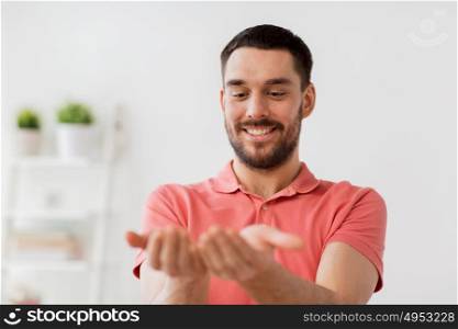 virtual reality, entertainment and people concept - happy man holding something imaginary on palms at home. happy man holding something imaginary at home