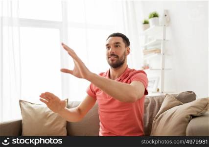 virtual reality, entertainment and people concept - happy man touching something imaginary at home. happy man touching something imaginary at home