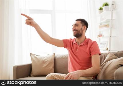 virtual reality, entertainment and people concept - happy man touching something imaginary at home. happy man touching something imaginary at home