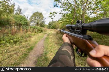 virtual reality game and violence concept - POV of male hands shooting with air rifle outdoors. POV of male hands shooting with air rifle