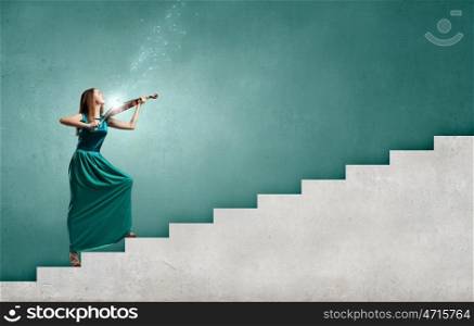 Virtuoso violin female player in green dress. Attractive violinist