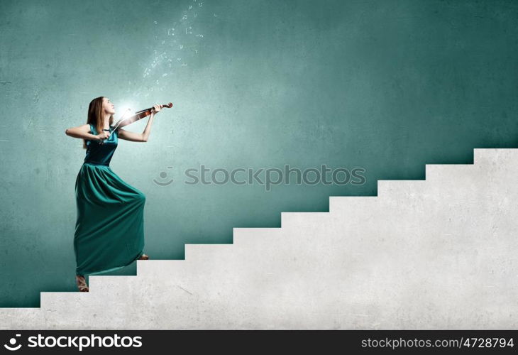 Virtuoso violin female player in green dress. Attractive violinist