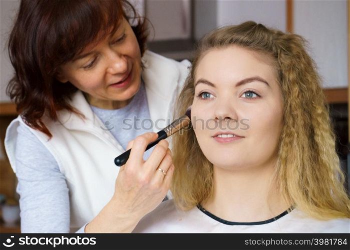 Visage concept. Close up woman getting make up on cheeks. Applying blush with brush by professional artist. Woman getting make up done by artist