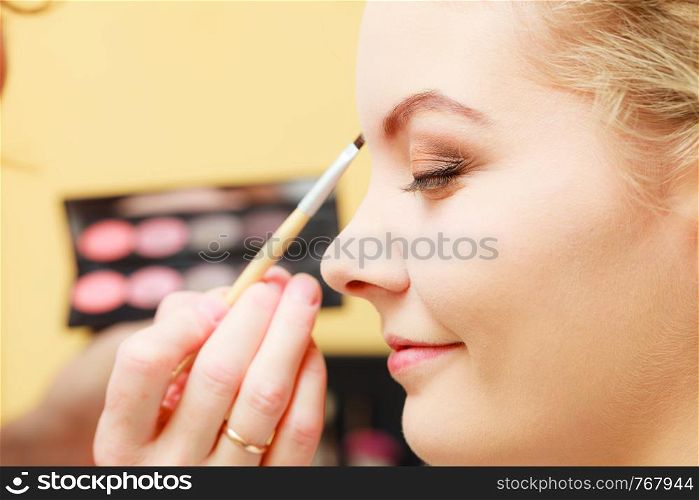 Visage concept. Close up woman getting make up on eyebrows. Applying eyeshadow on eyebrow with brush. Eyes closed.. Close up woman getting make up, eyebrows