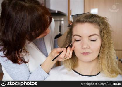 Visage concept. Close up woman getting make up on eyelids. Applying eyeshadow with brush by professional artist. Woman getting make up done by artist