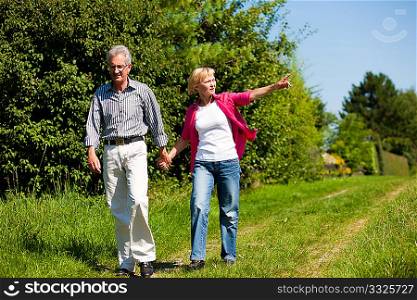 Visibly happy mature or senior couple outdoors arm in arm having a walk