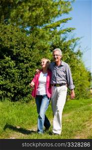 Visibly happy mature or senior couple outdoors arm in arm having a walk