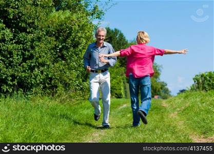 Visibly happy mature or senior couple outdoors having a walk in a playful way