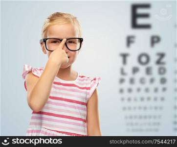 vision and children concept - smiling cute little girl in black glasses over eye test chart background. smiling little girl in glasses over eye test chart