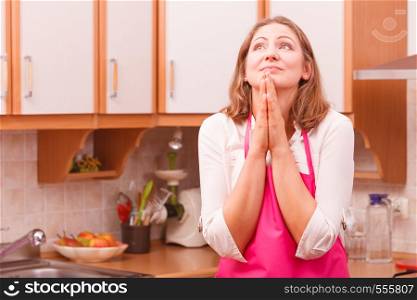 Vision and idea concept. Happy dreaming thinking woman in kitchen. Contemplating housewife wearing pink apron at home.. Dreaming housewife at home