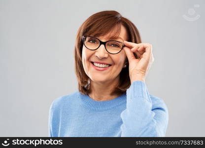 vision and old people concept - portrait of smiling senior woman in glasses over grey background. portrait of senior woman in glasses over grey