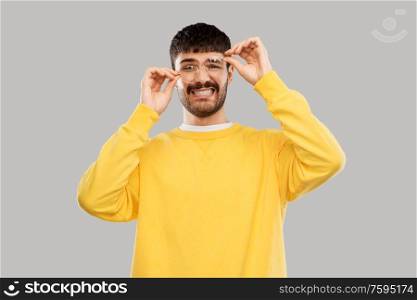 vision and people concept - goofy young man in glasses and yellow sweatshirt over grey background. goofy young man in glasses and yellow sweatshirt