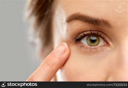 vision, beauty and people concept - close up of woman pointin finger to eye. close up of woman pointin finger to eye