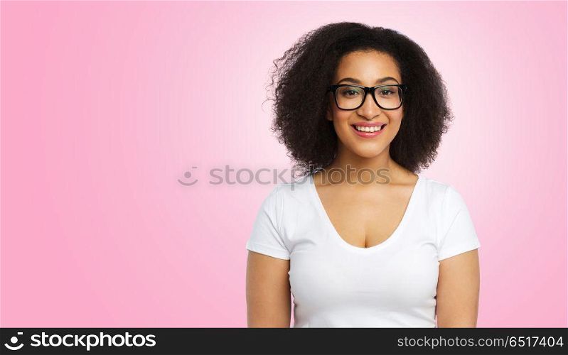 vision, body positive and people concept - happy african american woman in white t-shirt and glasses over pink background. african american woman in glasses and t-shirt. african american woman in glasses and t-shirt