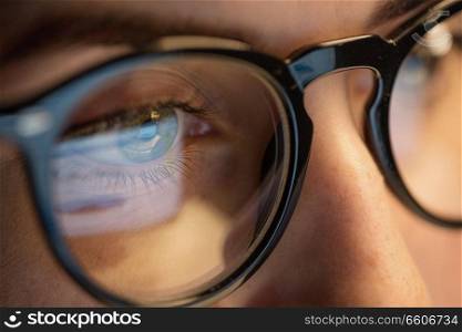 vision, business and education concept - close up of woman eyes in glasses looking at computer screen. close up of woman in glasses looking at screen