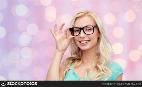 vision, education and people concept - happy smiling young woman or teenage girl glasses over pink holidays lights background