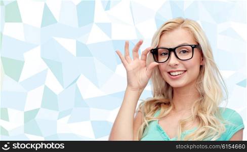 vision, education and people concept - happy smiling young woman or teenage girl glasses over blue low poly background