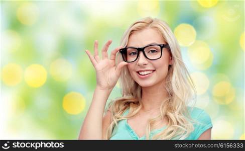 vision, education and people concept - happy smiling young woman or teenage girl glasses over summer green lights background
