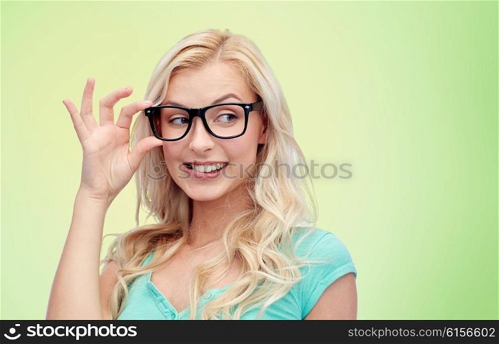 vision, education and people concept - happy smiling young woman or teenage girl glasses over green natural background