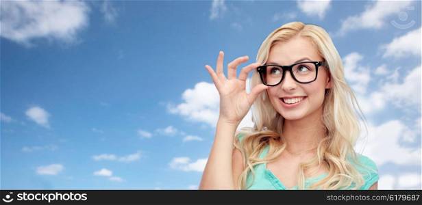vision, education and people concept - happy smiling young woman or teenage girl glasses over blue sky and clouds background