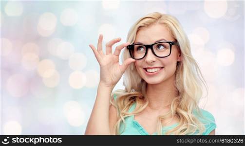 vision, education and people concept - happy smiling young woman or teenage girl glasses over holidays lights background