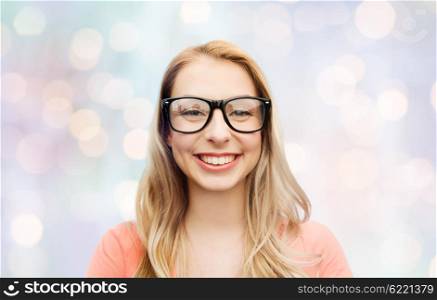 vision, education and people concept - happy smiling young woman or teenage girl eyeglasses over blue holidays lights background