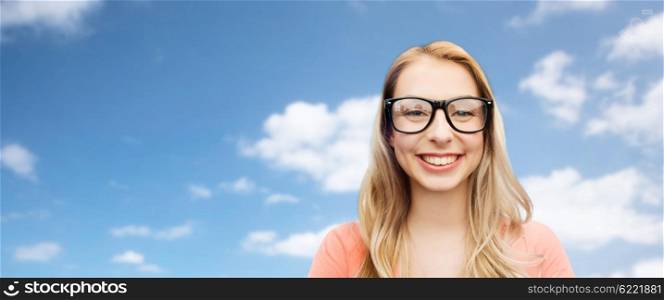 vision, education and people concept - happy smiling young woman or teenage girl eyeglasses over blue sky and clouds background