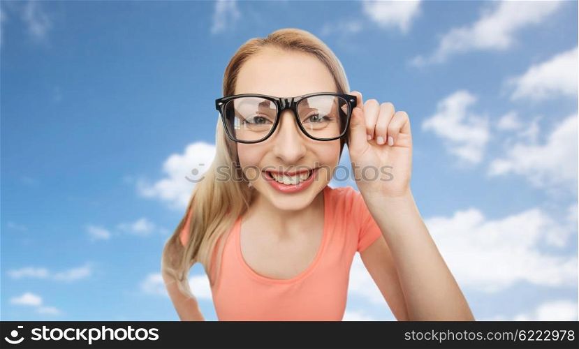vision, education and people concept - happy smiling young woman or teenage girl eyeglasses over blue sky and clouds background