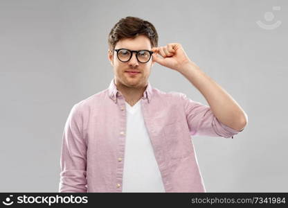 vision, education and people concept - young man in glasses over grey background. young man in glasses over grey background