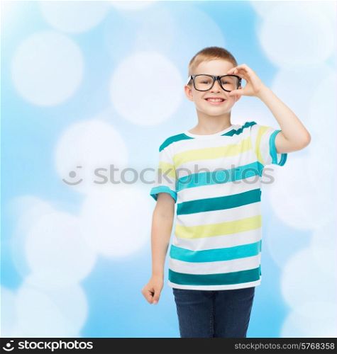 vision, education and school concept - smiling little boy in eyeglasses over blue background
