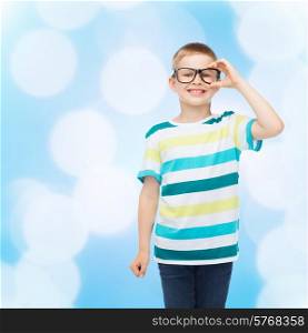 vision, education and school concept - smiling little boy in eyeglasses over blue background