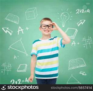 vision, education, childhood and school concept - smiling little boy in eyeglasses over green board with doodles background