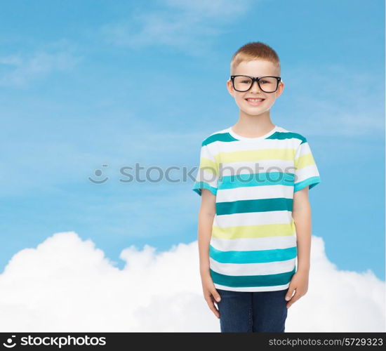 vision, education, childhood and school concept - smiling little boy in eyeglasses over blue sky with white cloud background