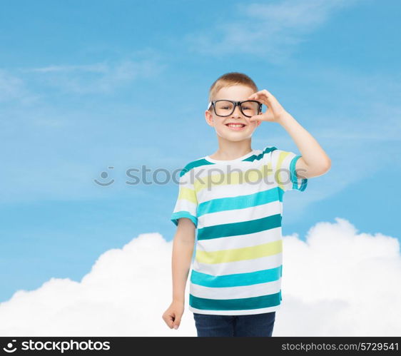 vision, education, childhood and school concept - smiling little boy in eyeglasses over blue sky with white cloud background