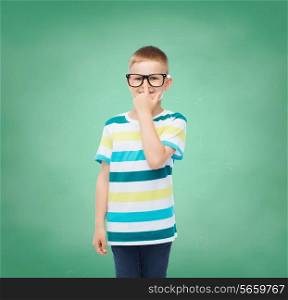 vision, education, childhood and school concept - smiling little boy in eyeglasses over green board background