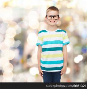 vision, education, holidays and school concept - smiling little boy in eyeglasses over sparkling background