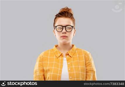 vision, education people concept - red haired teenage student girl in glasses and checkered shirt over grey background. red haired teenage student girl in glasses