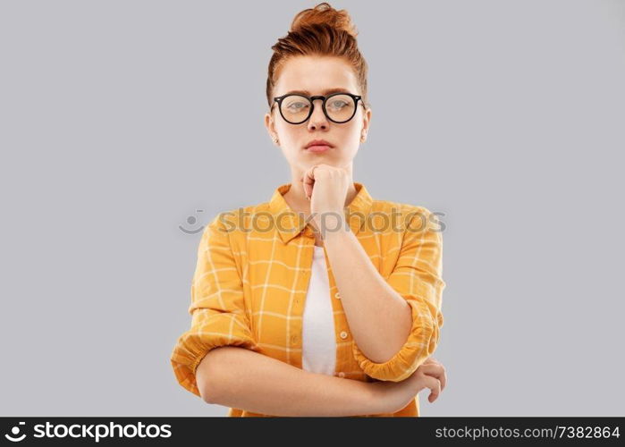 vision, education people concept - serious thinking red haired teenage student girl in glasses and checkered shirt over grey background. thinking redhead teenage student girl in glasses