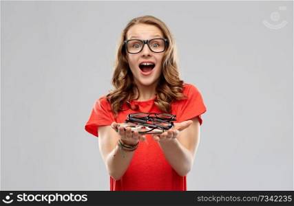 vision, education, school and emotions concept - surprised teenage student girl holding pile of glasses over grey background. surprised teenage girl holding pile of glasses