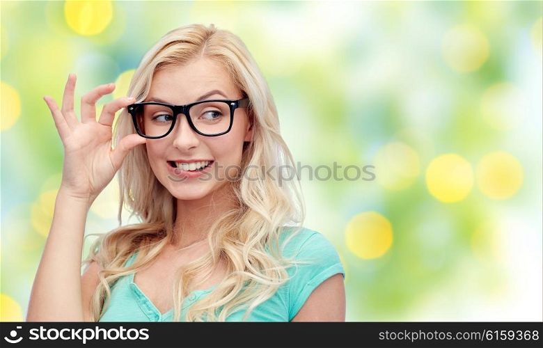vision, education, summer and people concept - happy smiling young woman or teenage girl glasses over green lights background