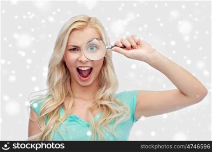 vision, exploration, investigation, education and people concept - happy smiling young woman or teenage girl looking through magnifying glass over snow