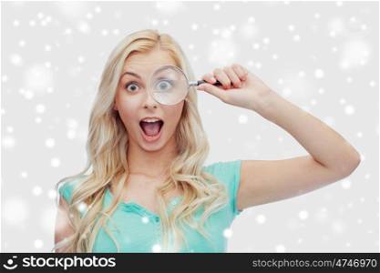 vision, exploration, investigation, education and people concept - happy young woman or teenage girl looking through magnifying glass over snow
